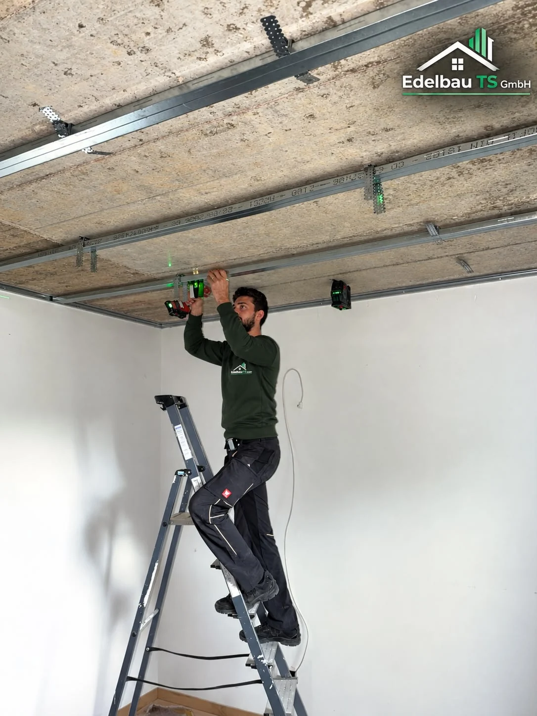 Ein Handwerker von Edelbau TS montiert eine Unterkonstruktion an der Decke