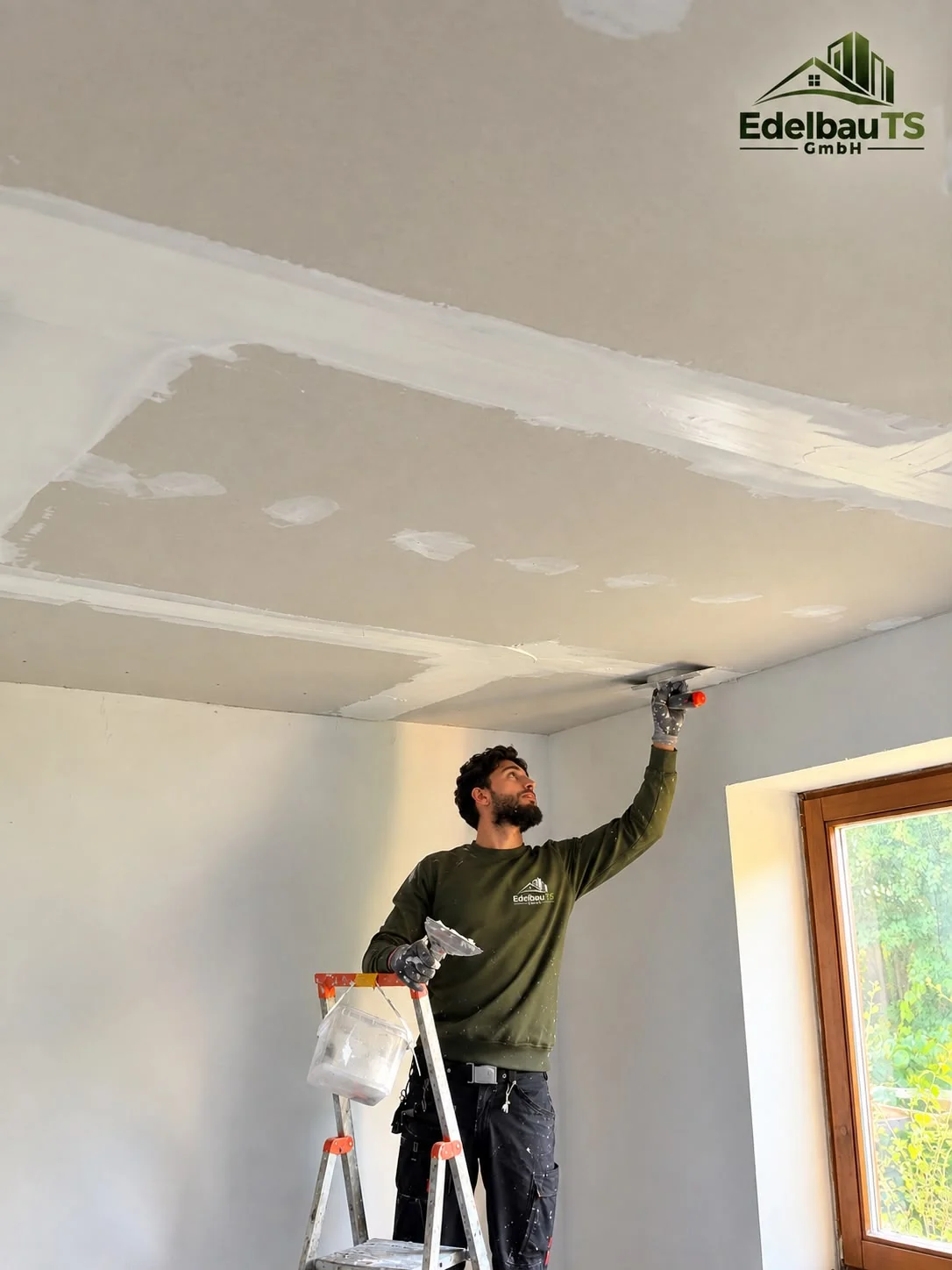Ein Handwerker beim Verspachteln einer Trockenbaudecke